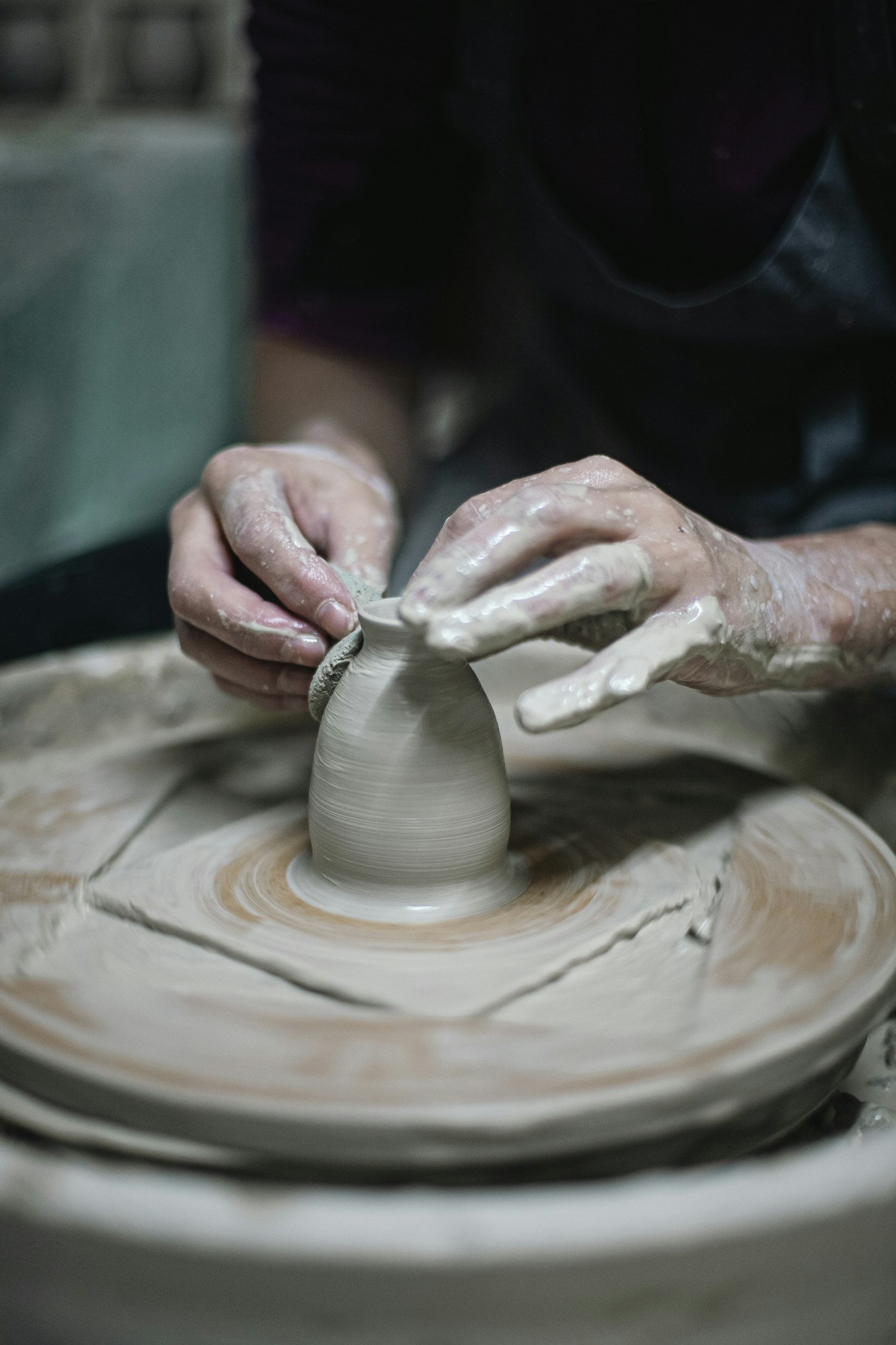 Hands shaping a small clay vessel